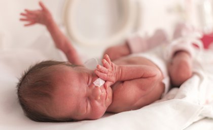 Newborn baby wearing a nappy with hands outstretched  